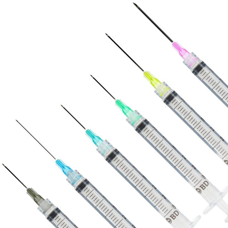 Five BD syringe-style needles with different colored tips (pink, yellow, green, blue, and gray) arranged diagonally on a plain white background.